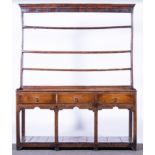 A George III oak dresser, with a three rack resting on a plinth section,