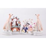 A pair of Staffordshire models of seated Greyhounds with hares naturalistically coloured,