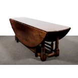 A large joined oak two leaf 'wake' table, oval top, cannon barrel legs, plain moulded stretchers,