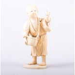 A Japanese carved ivory Okimono, probably Meiji, modelled as a boy standing with a basket of leaves,