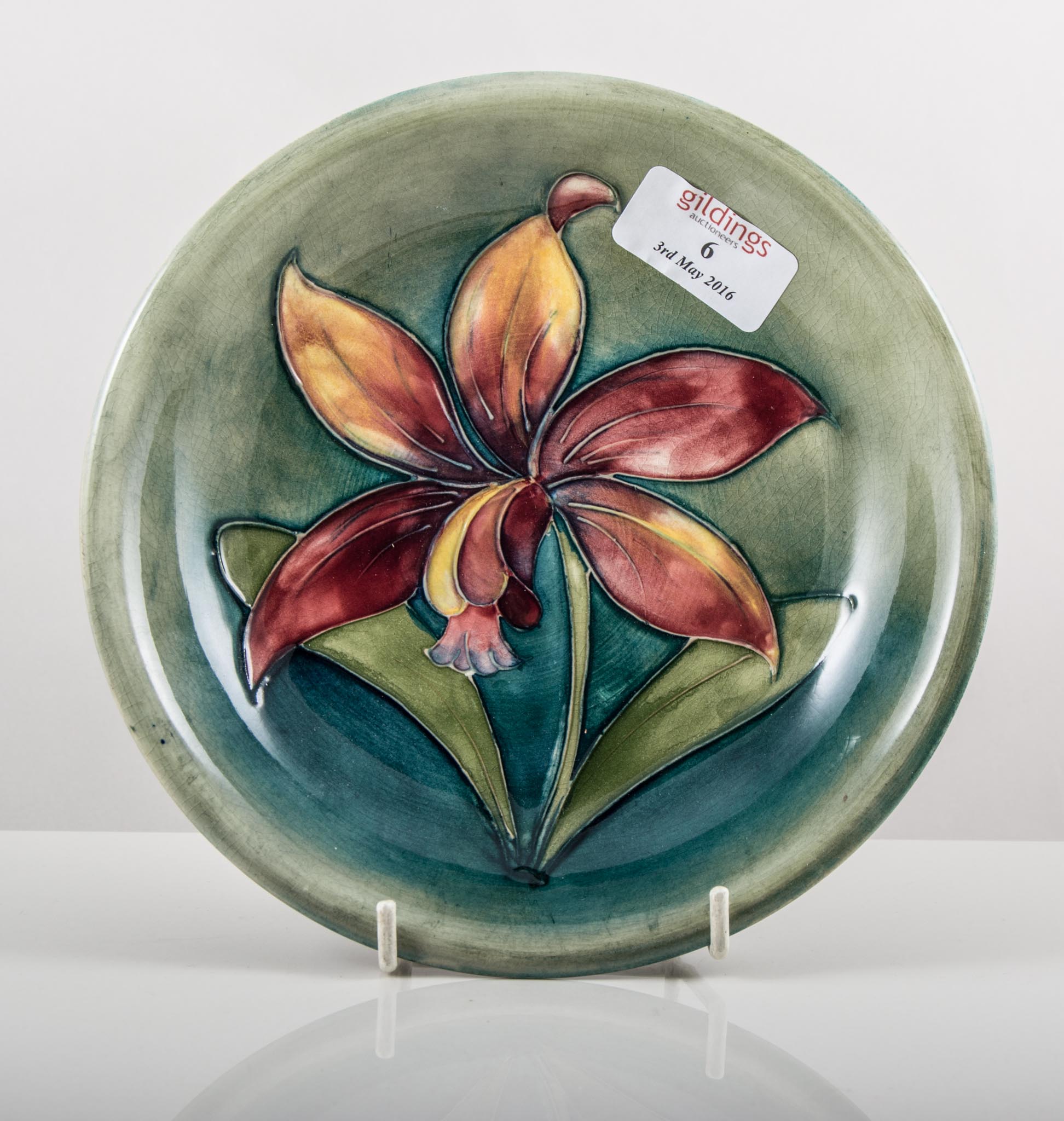 Walter Moorcroft, 'Freesia', a shallow dish/ plate, designed with a single flower, on shaded green,