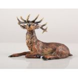 A bronze model of a recumbent stag, 8cm wide, two drilled holes to base.