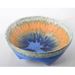 Ruskin, a pottery bowl, 1930, raised on tripod supports, running glazes in tones of orange and blue,