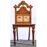 A Victorian Gothic Revival oak hall chair, carved arched back, set with two Minton tiles,