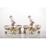 Pair of Berlin porcelain figural salts, each modelled with a cherub and two baskets,