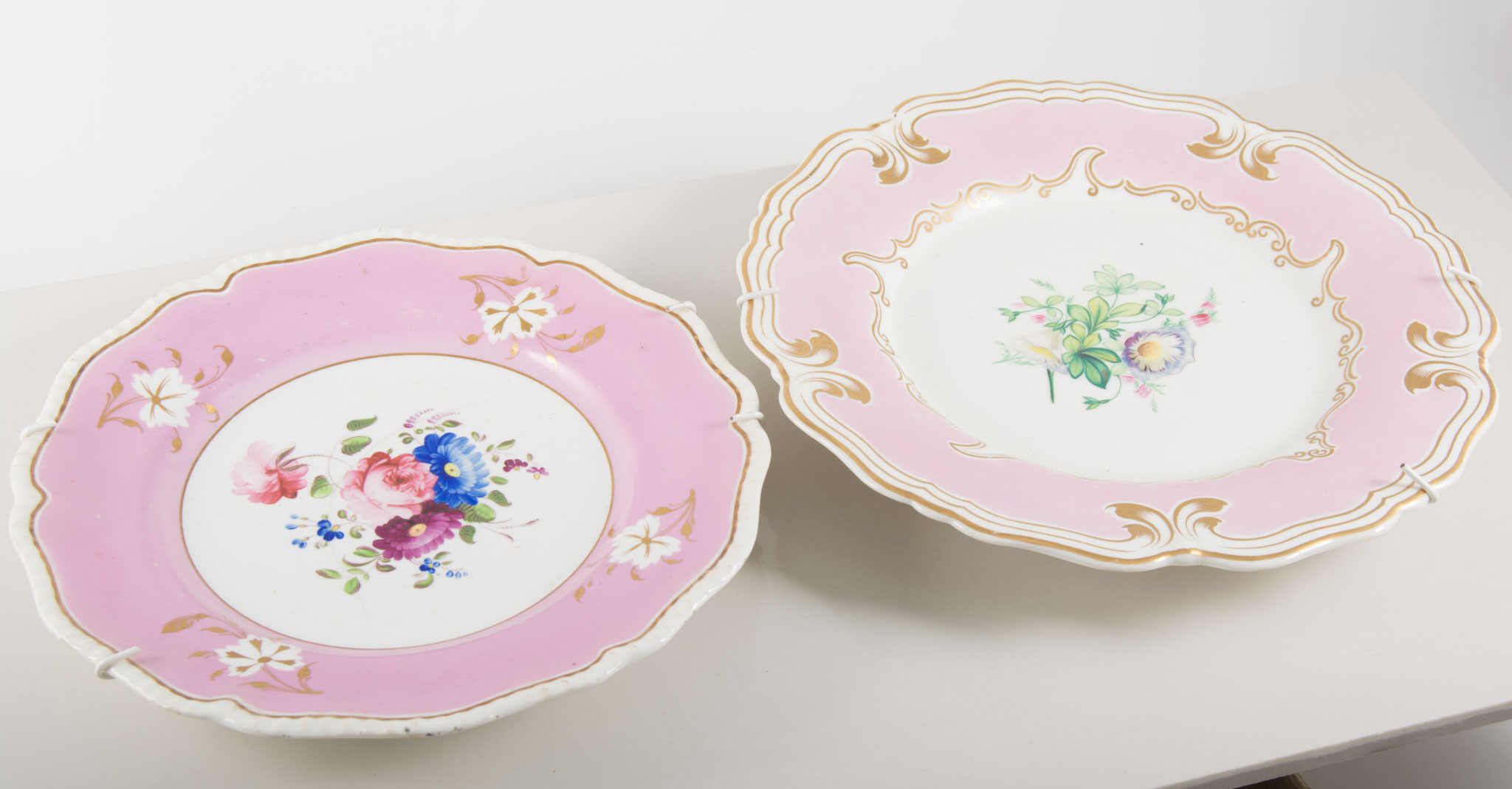 Collection of decorative hand painted plates, various floral designs, pink and green borders.