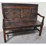 An oak bench seat with carved panels.