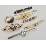 Small collection of gold and yellow metal brooches and pins.