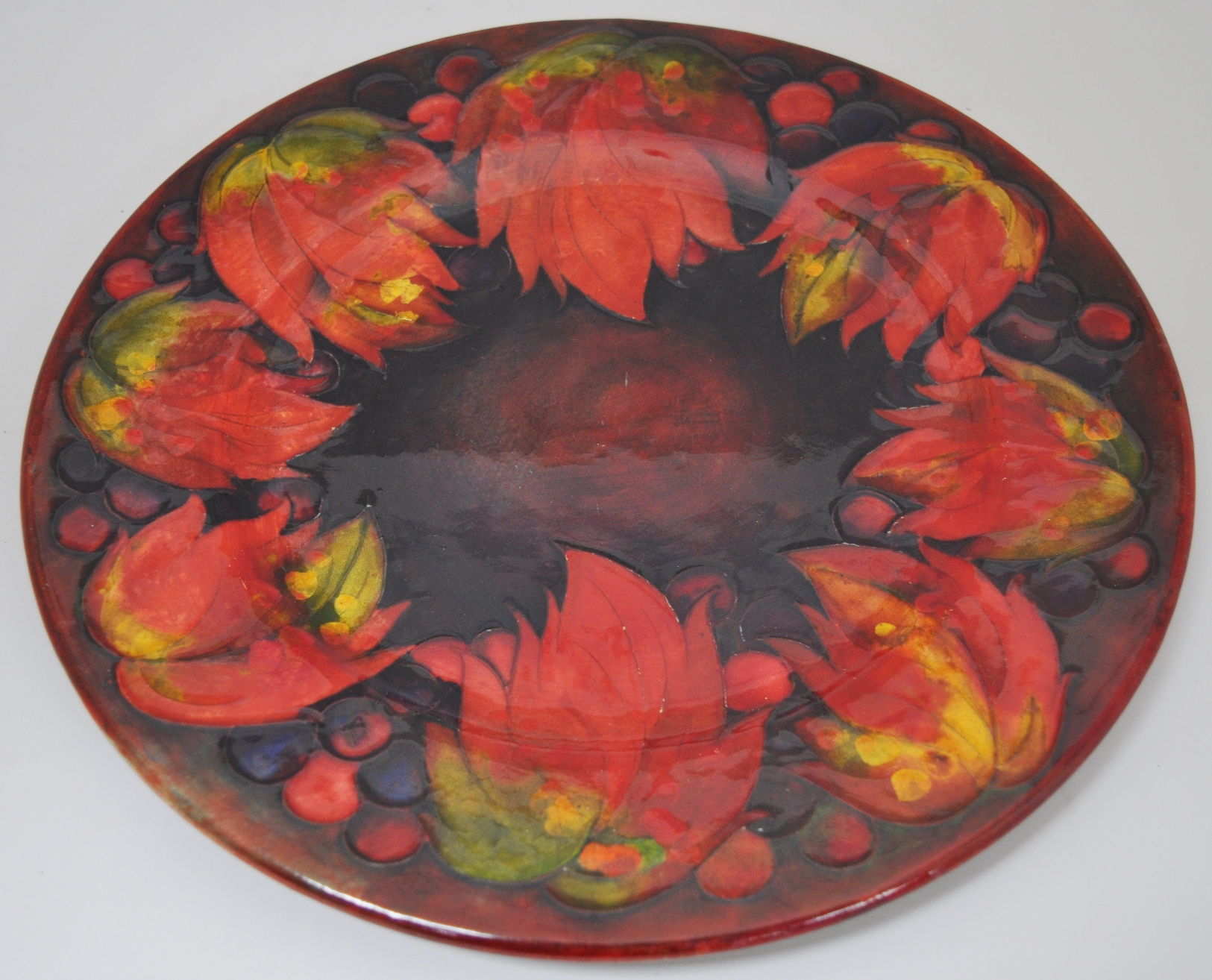 A Moorcroft plate, 'Leaf and Berry' design, flambé glaze, restored.