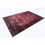 Persian pattern carpet, red ground with two lozenge medallions on a pole, meandering border,