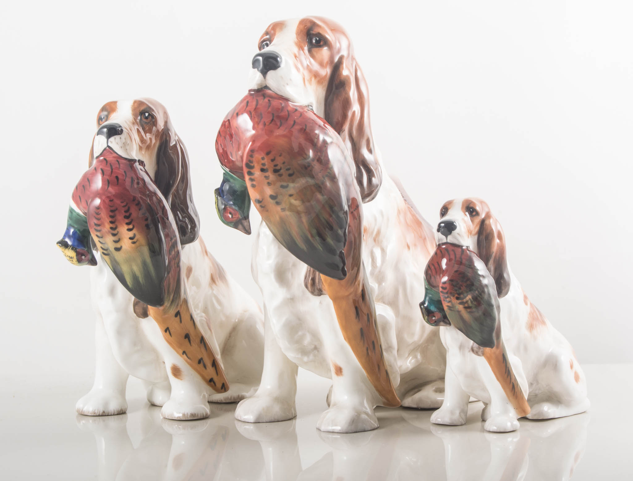 Set of three Royal Doulton graduating models, seated dogs with pheasants HN1001, height 17cm,