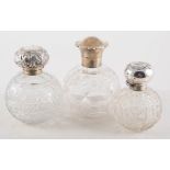 Three silver topped glass cologne bottles, with star cut bases, Birmingham 1915, 13cm,
