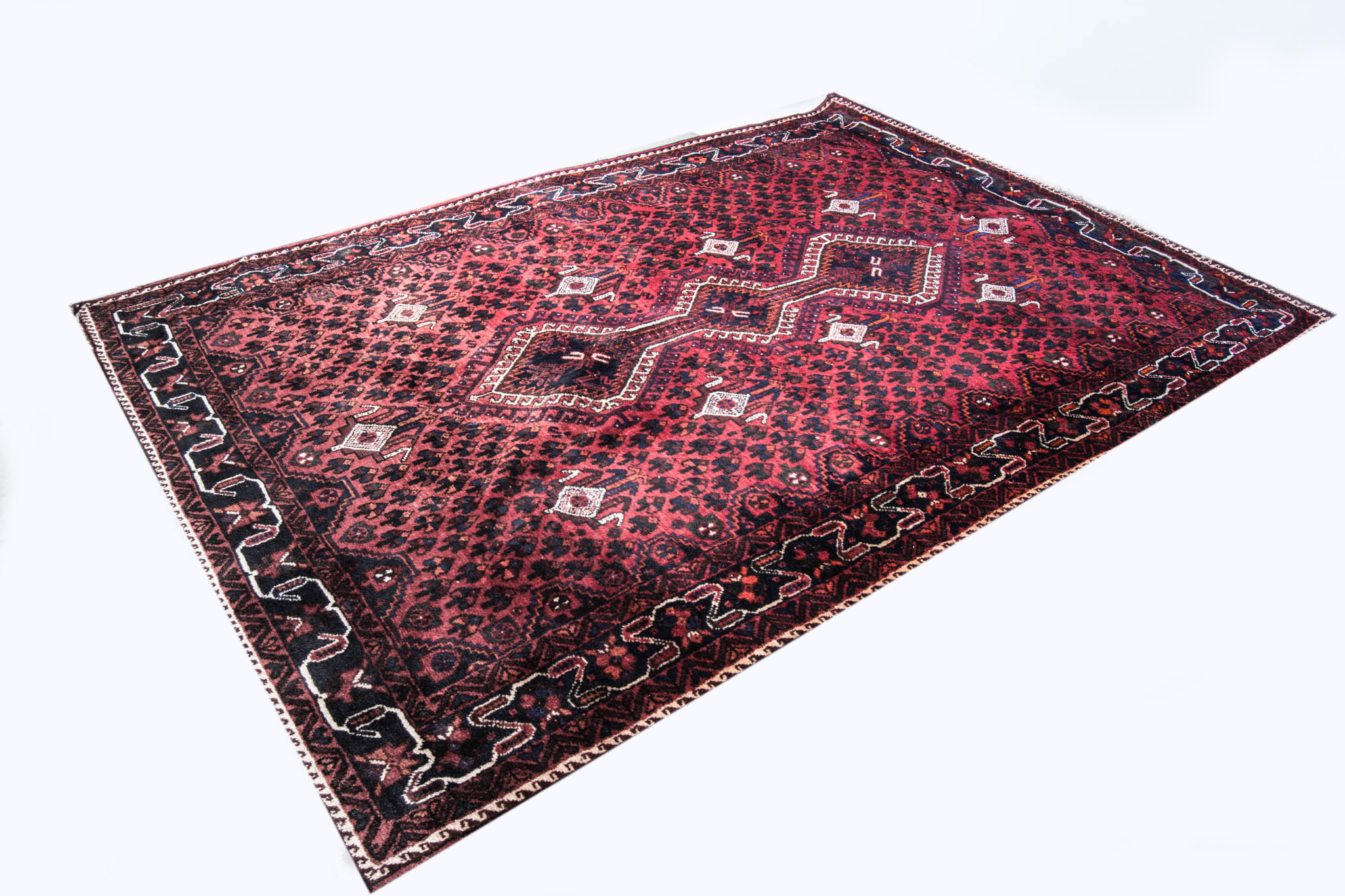 Persian pattern carpet, red ground with two lozenge medallions on a pole, meandering border,
