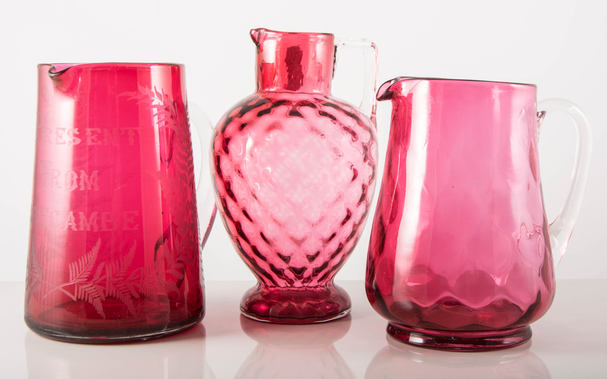 Cranberry glass tapering jug, 21cms and three other Cranberry jugs, (4).