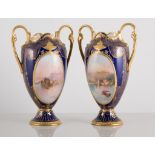 Pair of Royal Doulton cabinet vases, (both have repaired handles), painted with landscapes,