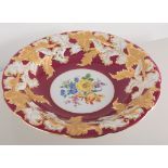 Two Meissen plates, painted with floral fields enclosed by maroon ground with gilt detailing,