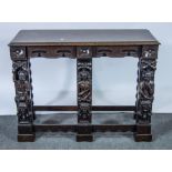 A carved oak side table, with 18th century style carytids, fitted with two frieze drawers,