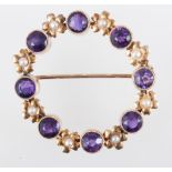 A yellow metal open circle garland brooch, individually milgrain set with eight amethysts,