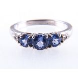 A tanzanite dress ring, three oval cut tanzanite with a brilliant cut stone to each side,