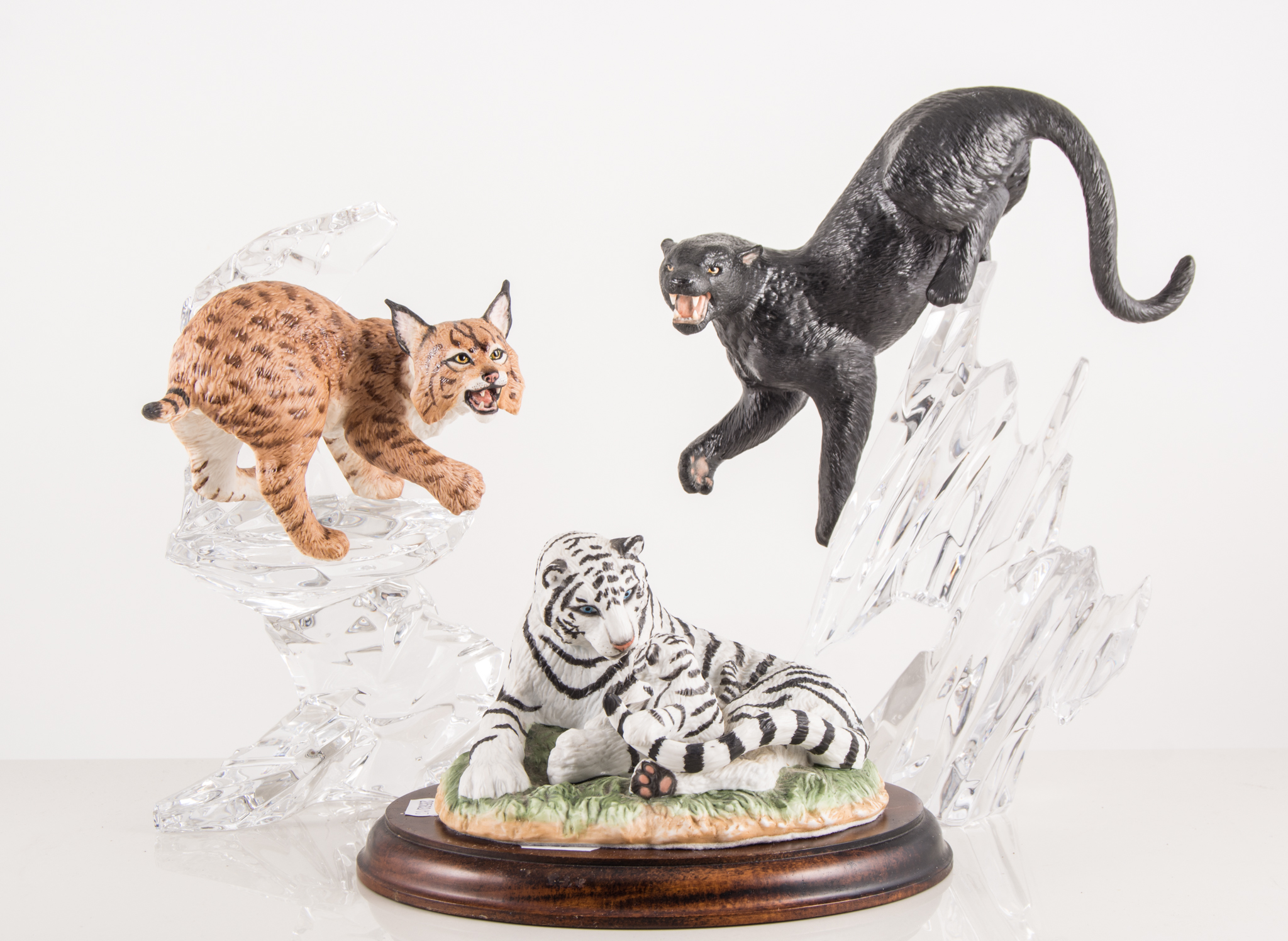 Four figures of big cats on glass bases, together with a wolf,