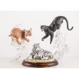 Four figures of big cats on glass bases, together with a wolf,