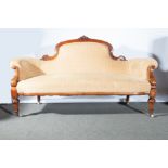 A Victorian walnut framed settee, arched back with a carved crest, scrolled arms, bow-front seat,