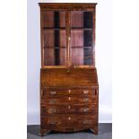 A George III mahogany bureau with a bookcase, cavetto moulded, glazed doors enclosing shelves,