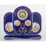 A blue glazed pottery three piece clock garniture, printed reserves, later dial, 30cm.