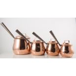 Four graduating copper pans.