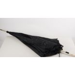 An Edwardian black moire silk parasol with black ruched lining and ivory coloured handle,