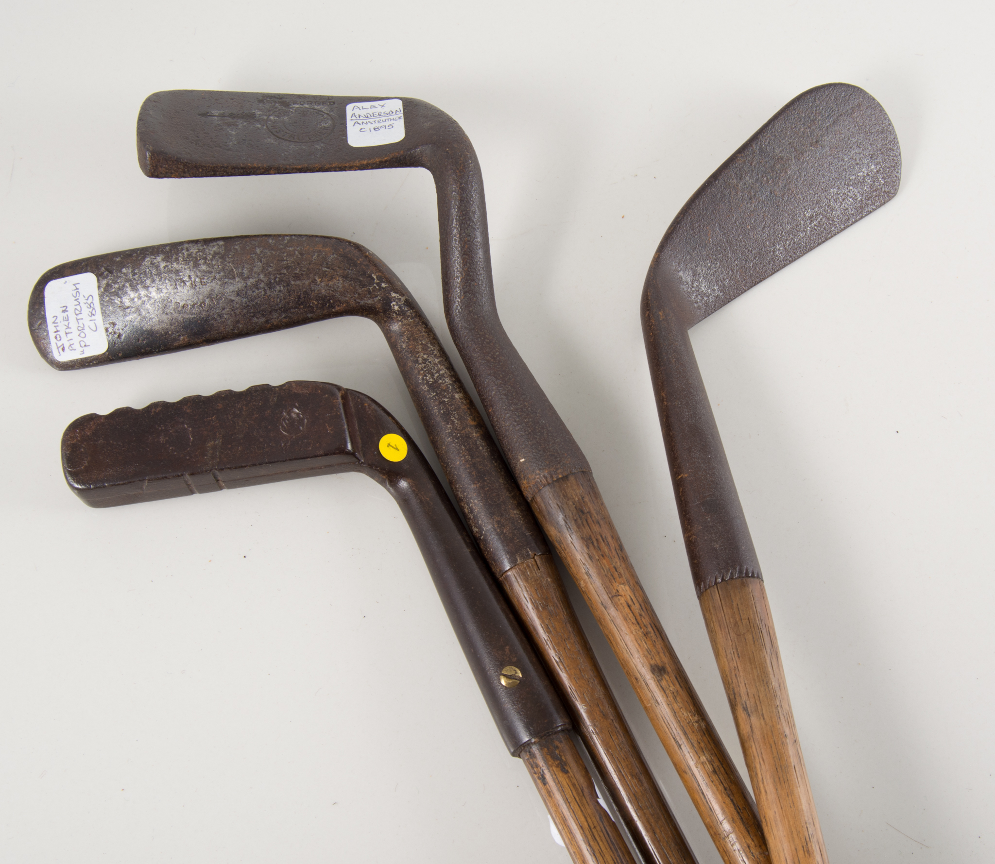 Four vintage hickory shafted golf clubs - an antique hand forged putter with square head and