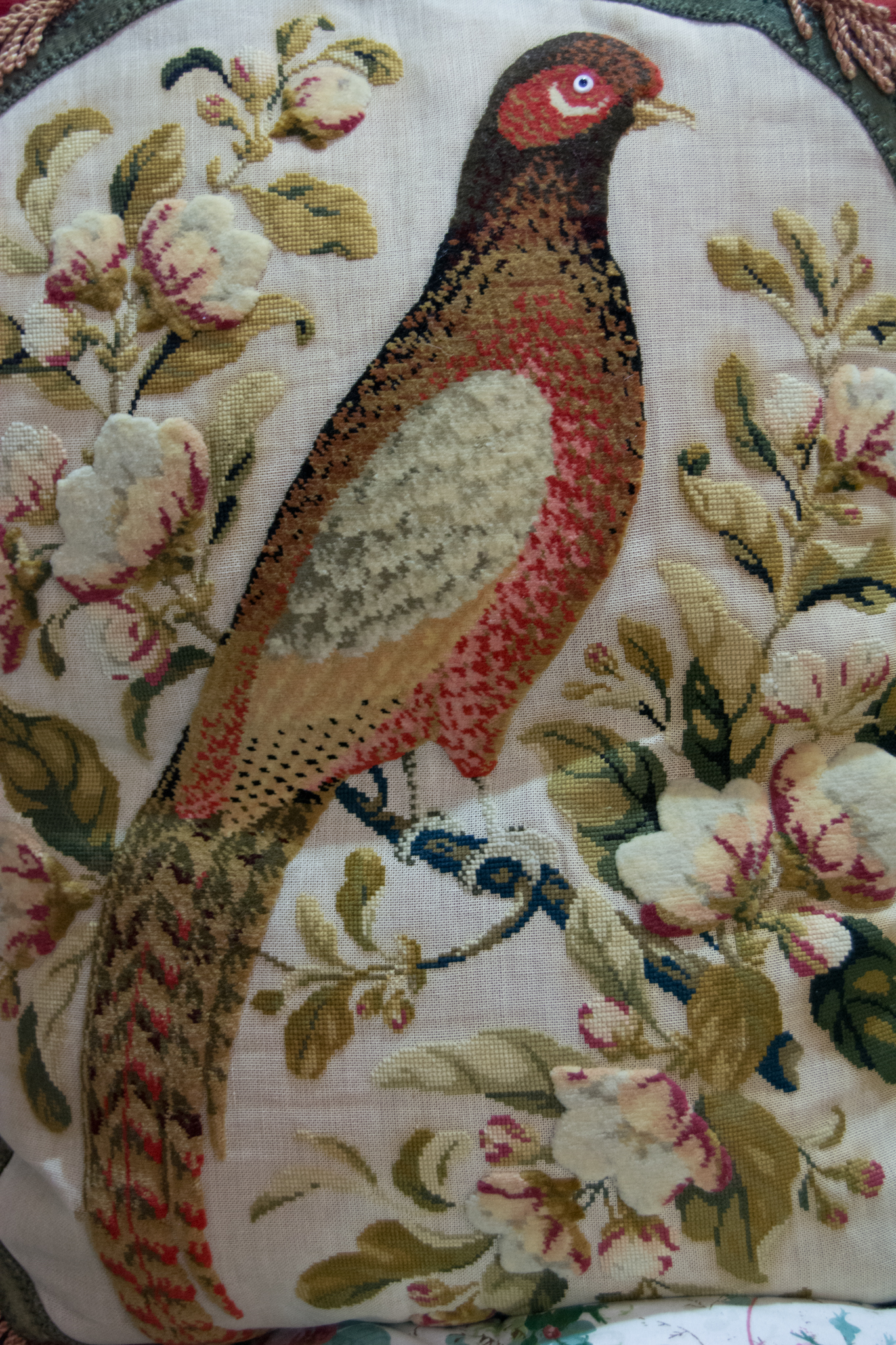 Large decorative red velvet cushion with oval panel of machine wool work bird sitting on a