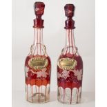 Pair of slice-cut ruby glass port and sherry decanters, with hexagonal stoppers.