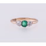 An emerald and diamond three stone ring, a step cut emerald 5mm x 4mm,