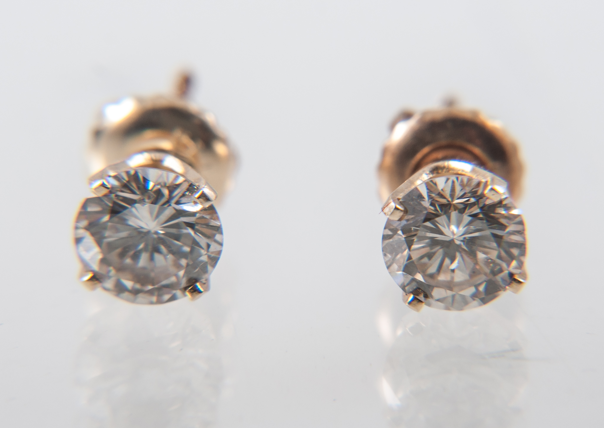 A pair of diamond single stone earrings, one brilliant cut half carat diamond four claw set to each,