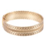 A hallmarked 14 carat yellow gold bracelet, 15mm wide flexible cuff with a satin finish,