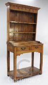 A small oak dresser, the back fitted with two shelves with iron cup hooks, above two frieze