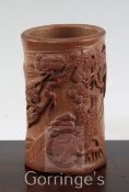 A Chinese bamboo brush pot, carved in high relief with a sage seated beneath a pine tree, on three