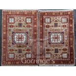 A pair of Kazak rugs, with central hooked medallion in a field of geometric motifs, on a beige