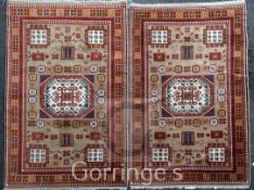 A pair of Kazak rugs, with central hooked medallion in a field of geometric motifs, on a beige