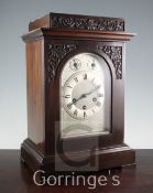 An early 20th century carved walnut mantel clock, with arched silvered dial and Junghans movement,