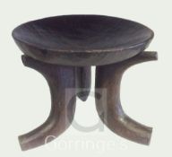 An Ethiopian Jimma hardwood stool, the dished seat raised on three scrolled legs, H 15.25in
