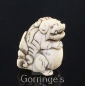 A Japanese ivory netsuke of a shi-shi, Edo period, seated and holding a ball, 4cm