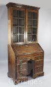 A George I oak kneehole bureau bookcase, with plain barred glazed doors over the fall enclosing a