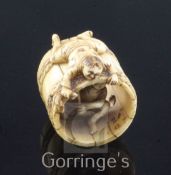 A Japanese ivory netsuke of two men constructing a barrel, Meiji period, one man lying on top of the