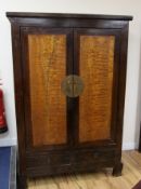 A Chinese hardwood two door cabinet, the base fitted with a long drawer