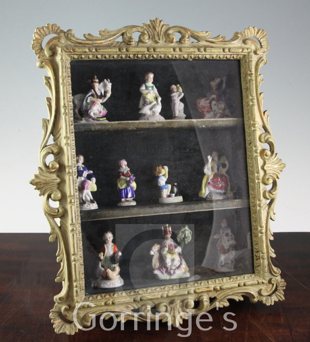 A collection of Chelsea style hard paste porcelain toy figures, contained in a green painted and