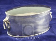 A George V silver oval biscuit box, with hinged lid, gadrooned borders and lion mask ring handles,