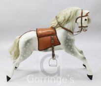 A dapple grey painted carved wood rocking horse, with leather saddle and bridle, lacking swing