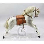A dapple grey painted carved wood rocking horse, with leather saddle and bridle, lacking swing